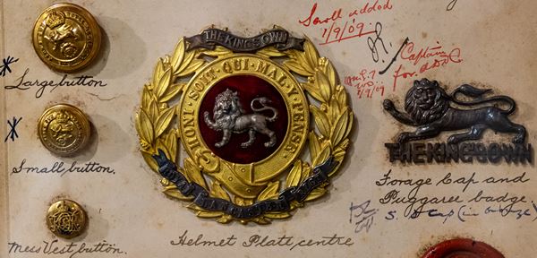 photo of several metal badges and buttons showing the King's Own lion emblem.